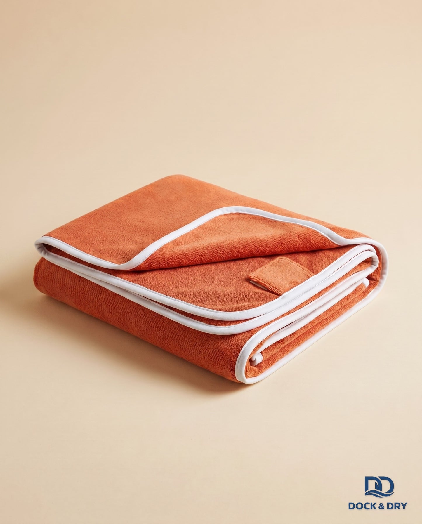Dock & Dry magnetic beach towel – Sunset Orange, folded with corner magnets